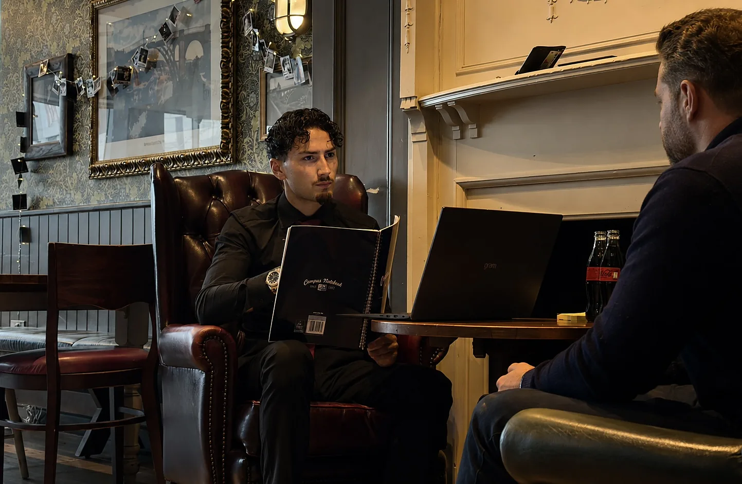 Talon Herring in a first meeting — armchair, notebook open, client across the table.