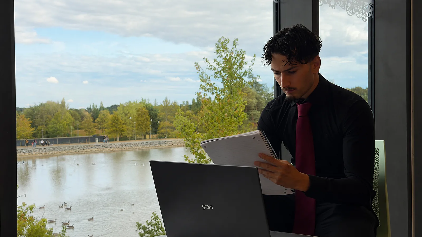 Reading back through the visit notes — notebook against the laptop, Telford outside the window.